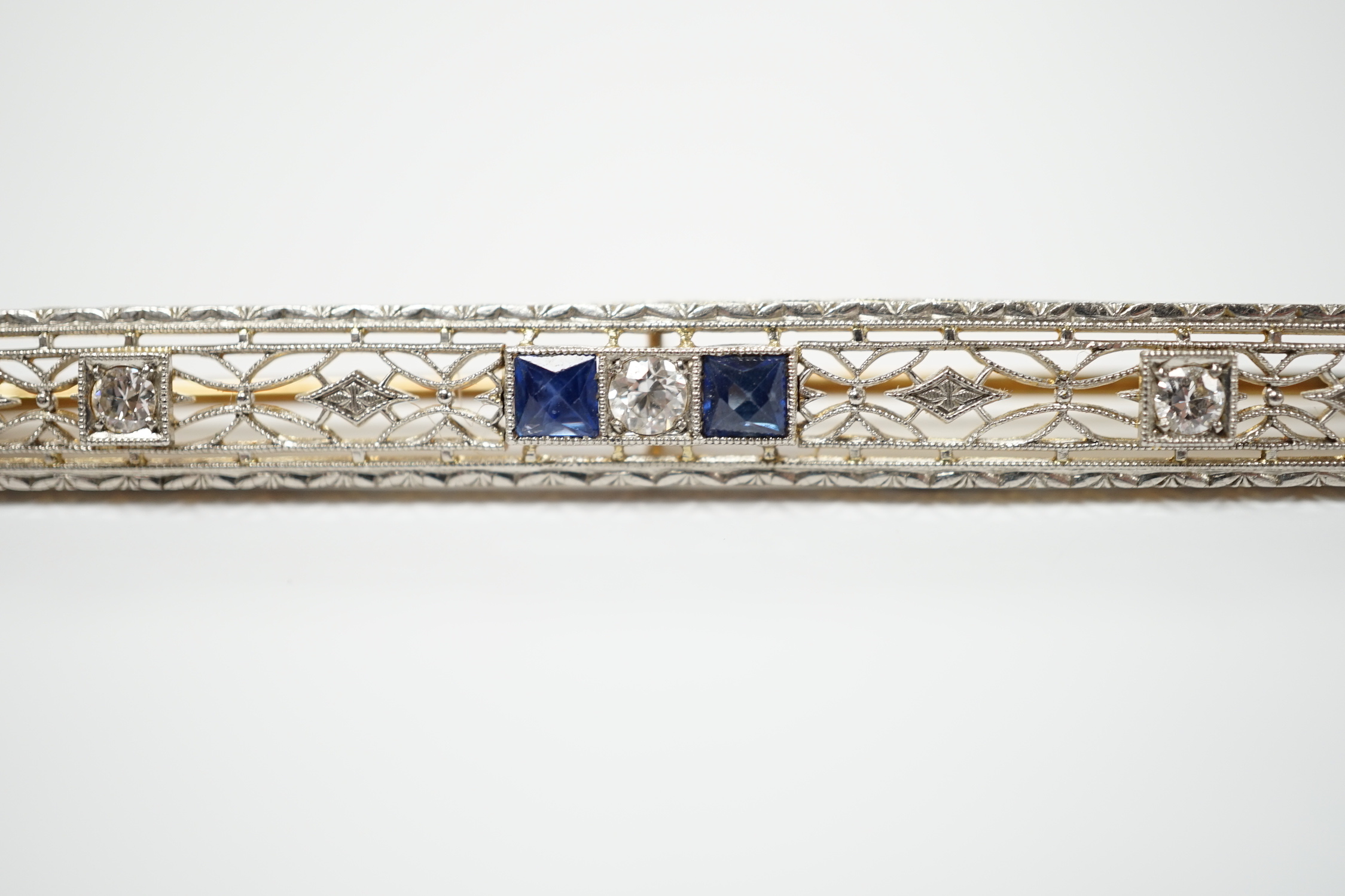 A Belle Époque style pierced 14k, sapphire and diamond cluster set bar brooch, 70mm, gross weight 5.5 grams.
